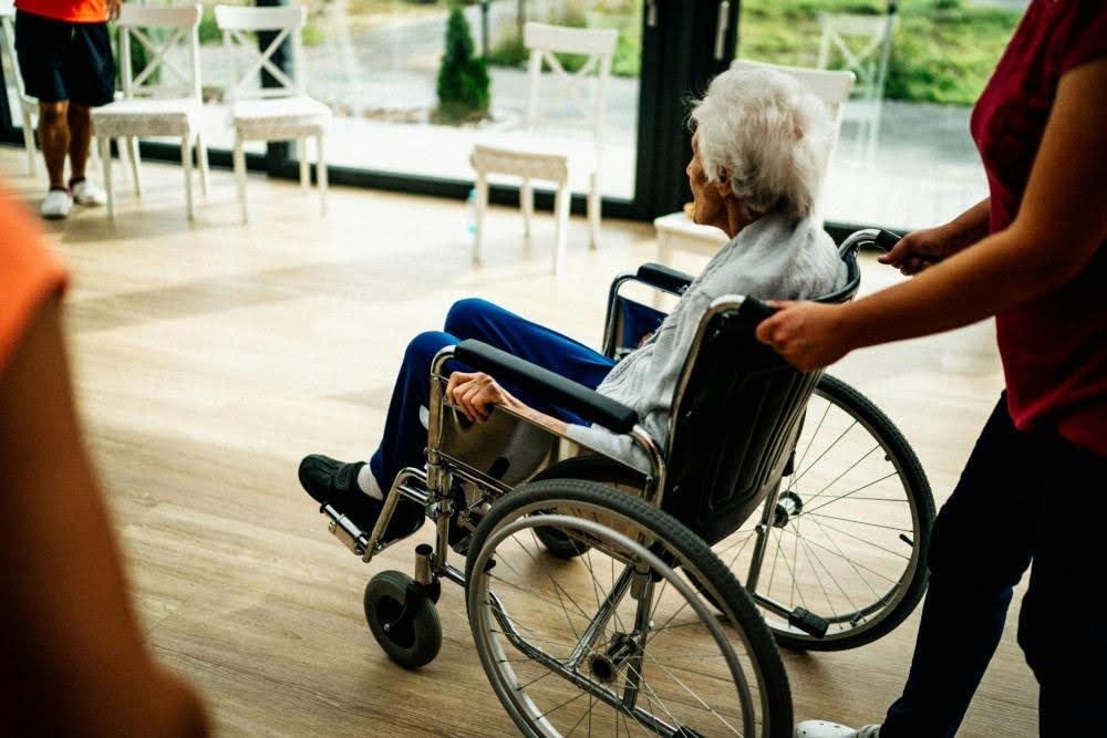 caregiver-pushing-elderly-on-wheelchair